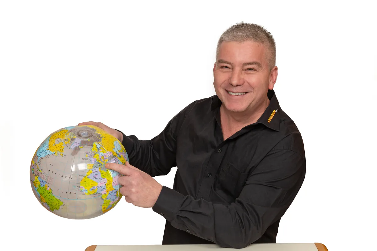 Roland Heusser, der Geschäftsführer von dem Carreiseunternehmen Heusser Touristik. Auf dem Bild sieht man Roland Heusser, den Geschäftsführer von Heusser Touristik, der eine Weltkugel hält.